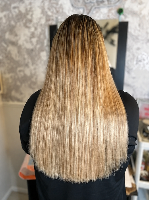 Long straight blonde hair extensions styled in a salon 