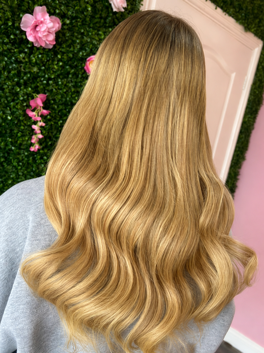 Golden blonde hair extensions styled in soft flowing waves 